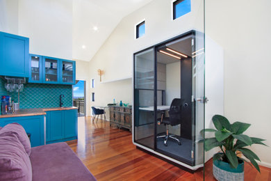 Large contemporary study room in Sydney with beige walls, medium hardwood floors, a built-in desk and brown floor.
