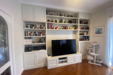 Immagine di un grande soggiorno contemporaneo chiuso con libreria, pareti bianche, parquet scuro, nessun camino, parete attrezzata e pavimento marrone