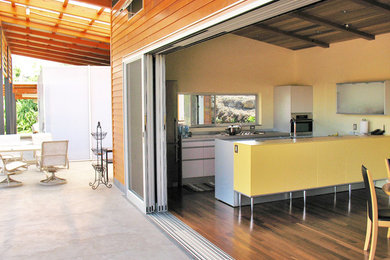 Inspiration for a small contemporary galley medium tone wood floor eat-in kitchen remodel in Hawaii with an integrated sink, flat-panel cabinets, yellow cabinets, stainless steel countertops, gray backsplash, stainless steel appliances and an island
