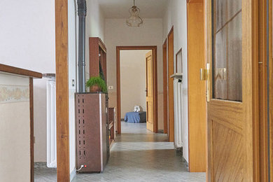 Immagine di un ingresso chic di medie dimensioni con pareti bianche, pavimento in gres porcellanato, una porta singola, una porta marrone e pavimento grigio