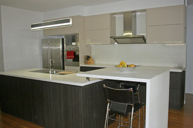 Large contemporary galley eat-in kitchen in Brisbane with a drop-in sink, quartz benchtops, white splashback, glass sheet splashback, stainless steel appliances and bamboo floors.