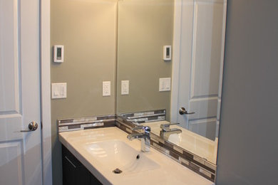 Inspiration for a mid-sized modern 3/4 beige tile, brown tile and mosaic tile vinyl floor alcove shower remodel in Calgary with flat-panel cabinets, dark wood cabinets, a two-piece toilet, beige walls, an integrated sink and solid surface countertops
