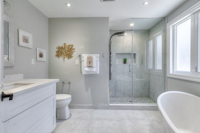 Large master bathroom in Toronto with shaker cabinets, white cabinets, a freestanding tub, a curbless shower, a one-piece toilet, white tile, porcelain tile, grey walls, porcelain floors, an undermount sink, quartzite benchtops, white benchtops and white floor.