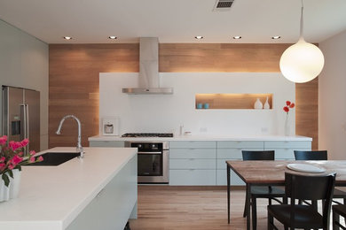 Eat-in kitchen - contemporary eat-in kitchen idea in Austin with stainless steel appliances, flat-panel cabinets, blue cabinets, quartz countertops, white backsplash and stone slab backsplash