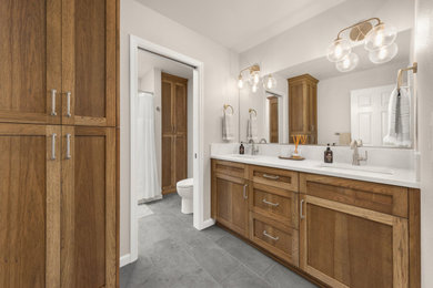 Bathroom - mid-sized transitional ceramic tile, gray floor and double-sink bathroom idea in Portland with shaker cabinets, medium tone wood cabinets, a one-piece toilet, beige walls, a drop-in sink, quartz countertops, white countertops and a built-in vanity