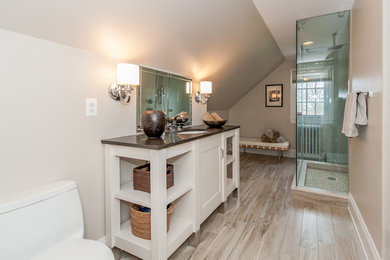 This is an example of a mid-sized transitional master bathroom in Baltimore with furniture-like cabinets, white cabinets, an alcove shower, a two-piece toilet, beige tile, porcelain tile, beige walls, light hardwood floors, an undermount sink, granite benchtops, beige floor and a hinged shower door.