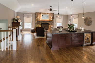 Inspiration for a large timeless open concept medium tone wood floor family room remodel in Boston with beige walls, a standard fireplace, a stone fireplace and a media wall