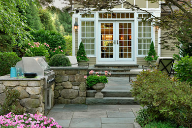 Inspiration for a mid-sized traditional partial sun backyard stone landscaping in Boston with a fire pit.