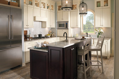 Inspiration for a mid-sized transitional l-shaped vinyl floor and brown floor open concept kitchen remodel in Minneapolis with an undermount sink, beaded inset cabinets, white cabinets, granite countertops, white backsplash, ceramic backsplash, stainless steel appliances and an island