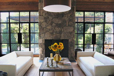 Photo of a country living room in New York with a stone fireplace surround and no tv.