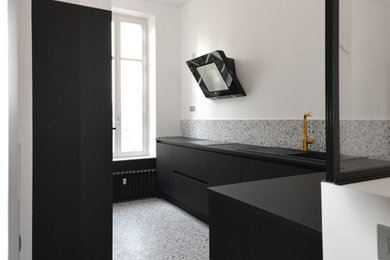 Réalisation d'une cuisine tradition avec un évier encastré, des portes de placard noires, un électroménager noir, un sol en terrazzo, un sol blanc et plan de travail noir.