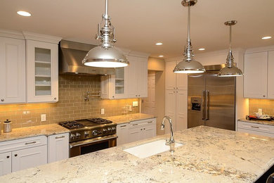Enclosed kitchen - large traditional l-shaped medium tone wood floor and brown floor enclosed kitchen idea in Orlando with an undermount sink, glass-front cabinets, white cabinets, granite countertops, beige backsplash, subway tile backsplash, stainless steel appliances and an island