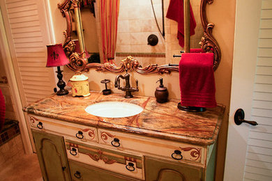 Mid-sized mediterranean bathroom in Sacramento with an undermount sink, raised-panel cabinets, green cabinets, granite benchtops, a drop-in tub, an alcove shower, beige tile, stone tile, beige walls and travertine floors.