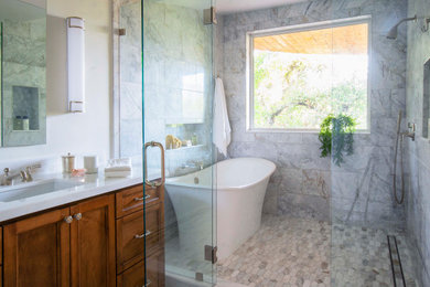 Example of a large transitional master gray tile and marble tile marble floor and gray floor bathroom design in Los Angeles with white walls, an undermount sink, marble countertops, a hinged shower door, white countertops, a niche, a built-in vanity, recessed-panel cabinets and medium tone wood cabinets
