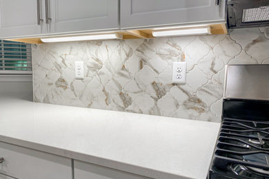 Elegant kitchen photo in Other with white backsplash, mosaic tile backsplash, stainless steel appliances and white countertops