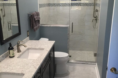 Inspiration for a mid-sized timeless master black and white tile, gray tile and marble tile gray floor and marble floor bathroom remodel in DC Metro with furniture-like cabinets, dark wood cabinets, a two-piece toilet, blue walls, an undermount sink, a hinged shower door and quartzite countertops