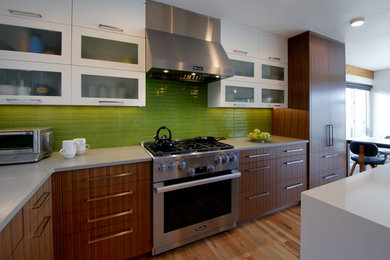 Photo of a mid-sized contemporary l-shaped open plan kitchen in Seattle with a single-bowl sink, flat-panel cabinets, medium wood cabinets, quartz benchtops, green splashback, ceramic splashback, stainless steel appliances, light hardwood floors, with island and grey benchtop.