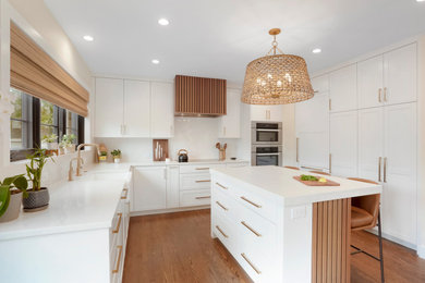 Example of a large transitional u-shaped medium tone wood floor eat-in kitchen design in Denver with a farmhouse sink, shaker cabinets, white cabinets, quartz countertops, white backsplash, quartz backsplash, paneled appliances, an island and white countertops