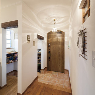 他の地域の片開きドアアジアンスタイルのおしゃれな玄関ホール (白い壁、テラコッタタイルの床、木目調のドア、オレンジの床) の写真