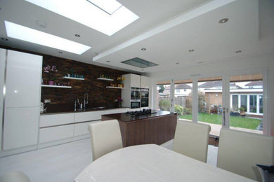 Contemporary single-wall kitchen/diner in London with integrated appliances, porcelain flooring, an island and beige floors.