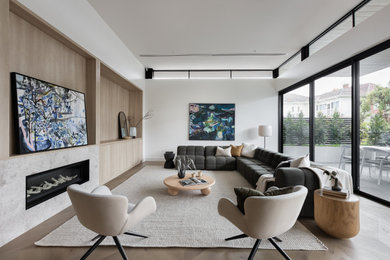 Modelo de salón minimalista con paredes blancas, suelo de madera clara, chimenea lineal y suelo beige