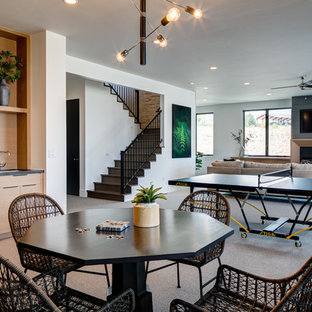 Modelo de sótano actual, grande, con paredes blancas, moqueta, chimenea tradicional, marco de chimenea de madera y suelo gris