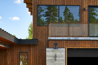 Immagine della facciata di una casa grande marrone a due piani con rivestimento in legno