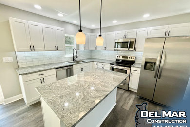 Mid-sized mountain style l-shaped vinyl floor and gray floor eat-in kitchen photo in Baltimore with an undermount sink, shaker cabinets, white cabinets, granite countertops, white backsplash, ceramic backsplash, stainless steel appliances, an island and gray countertops