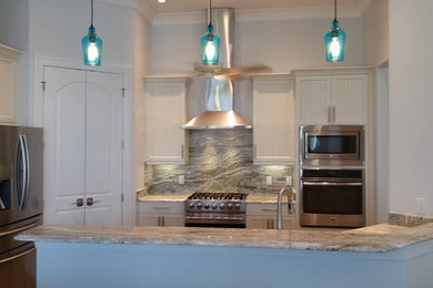 Open concept kitchen - contemporary single-wall travertine floor open concept kitchen idea in Miami with stone slab backsplash, stainless steel appliances, a double-bowl sink, white cabinets, multicolored backsplash, an island and granite countertops