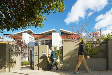 Photo of a contemporary two-storey yellow townhouse exterior in Perth with mixed siding and a metal roof.
