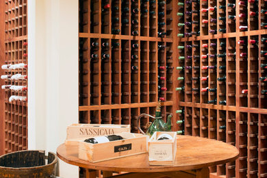 This is an example of a large traditional wine cellar in New York with light hardwood floors, storage racks and orange floor.