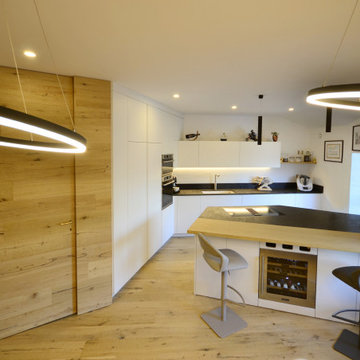 Cucina laccato bianco con inserti in rovere e parete rivestita in rovere