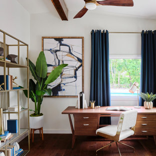 Mittelgroßes Retro Arbeitszimmer mit Arbeitsplatz, weißer Wandfarbe, braunem Holzboden, freistehendem Schreibtisch, braunem Boden und freigelegten Dachbalken in Austin