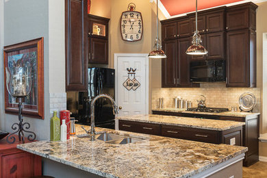Eat-in kitchen - large farmhouse u-shaped ceramic tile eat-in kitchen idea in Dallas with an undermount sink, raised-panel cabinets, dark wood cabinets, granite countertops, beige backsplash, ceramic backsplash, black appliances and an island