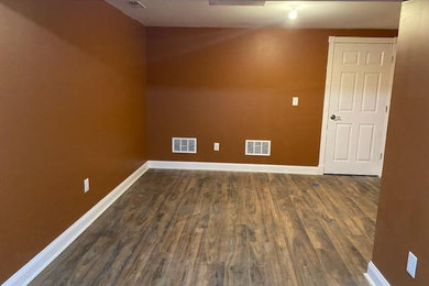 Foto de sótano clásico de tamaño medio sin chimenea con bar en casa, suelo laminado y suelo marrón