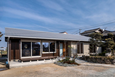 Ejemplo de fachada de casa gris de una planta con revestimiento de estuco, tejado a dos aguas, tejado de metal y panel y listón