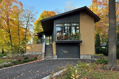 Mid-sized 1960s yellow two-story brick exterior home photo in Montreal with a metal roof and a gray roof