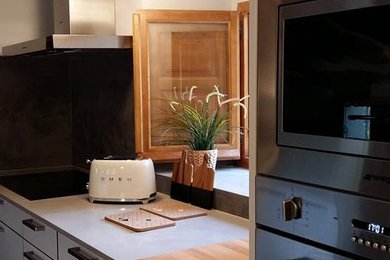 他の地域にある高級な中くらいなトランジショナルスタイルのおしゃれなキッチン (フラットパネル扉のキャビネット、白いキャビネット、グレーのキッチンパネル、シルバーの調理設備、グレーの床、グレーのキッチンカウンター、表し梁) の写真