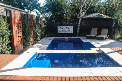 This is an example of a mid-sized contemporary backyard pool in Melbourne with natural stone pavers.