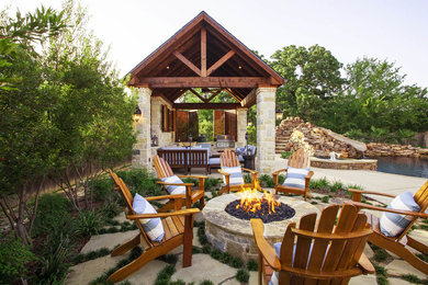 Photo of a mid-sized country backyard patio in Dallas with a fire feature, natural stone pavers and no cover.