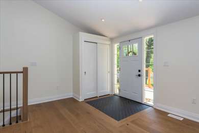 Entryway - transitional medium tone wood floor and brown floor entryway idea in Toronto with white walls and a white front door