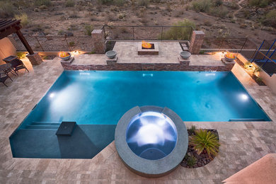 Photo of a large modern backyard custom-shaped pool in Phoenix with a water feature and natural stone pavers.