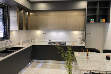 Design ideas for a medium sized modern grey and black l-shaped enclosed kitchen with a double-bowl sink, flat-panel cabinets, black cabinets, marble worktops, white splashback, marble splashback, black appliances, porcelain flooring, an island, white floors, white worktops, a drop ceiling and feature lighting.