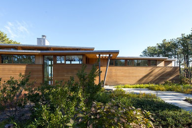 This is an example of a mid-sized modern one-storey brown house exterior in Boston with wood siding and a flat roof.