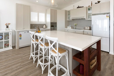 Inspiration for a beach style l-shaped eat-in kitchen in Central Coast with an undermount sink, shaker cabinets, beige cabinets, quartz benchtops, brown splashback, subway tile splashback, white appliances, vinyl floors and with island.