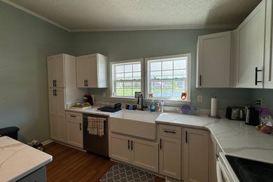 Example of a mid-sized cottage l-shaped vinyl floor and brown floor eat-in kitchen design in Other with a farmhouse sink, shaker cabinets, white cabinets, quartz countertops, beige backsplash, quartz backsplash, stainless steel appliances, an island and beige countertops