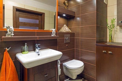 Mid-sized trendy brown tile and porcelain tile porcelain tile bathroom photo in Other with flat-panel cabinets, dark wood cabinets, a wall-mount toilet, brown walls and a vessel sink