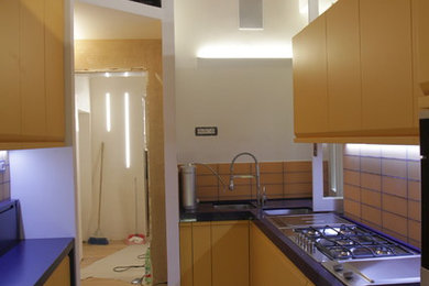 Idee per una cucina minimal di medie dimensioni con lavello sottopiano, ante lisce, ante arancioni, top in quarzo composito, paraspruzzi blu, paraspruzzi in marmo, elettrodomestici in acciaio inossidabile e pavimento in travertino