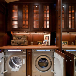 Foto de lavadero clásico, extra grande, con armarios tipo vitrina, puertas de armario de madera en tonos medios, moqueta, lavadora y secadora juntas, suelo beige y encimeras marrones