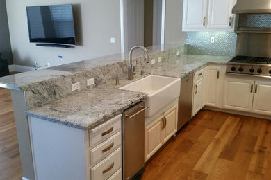 This is an example of a mid-sized traditional u-shaped eat-in kitchen in San Francisco with a farmhouse sink, beaded inset cabinets, white cabinets, granite benchtops, grey splashback, mosaic tile splashback, stainless steel appliances, medium hardwood floors and no island.